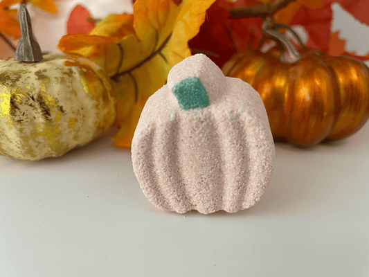 Natural mini pumpkin bath bomb with decorative pumpkins and fall leaves in the background.