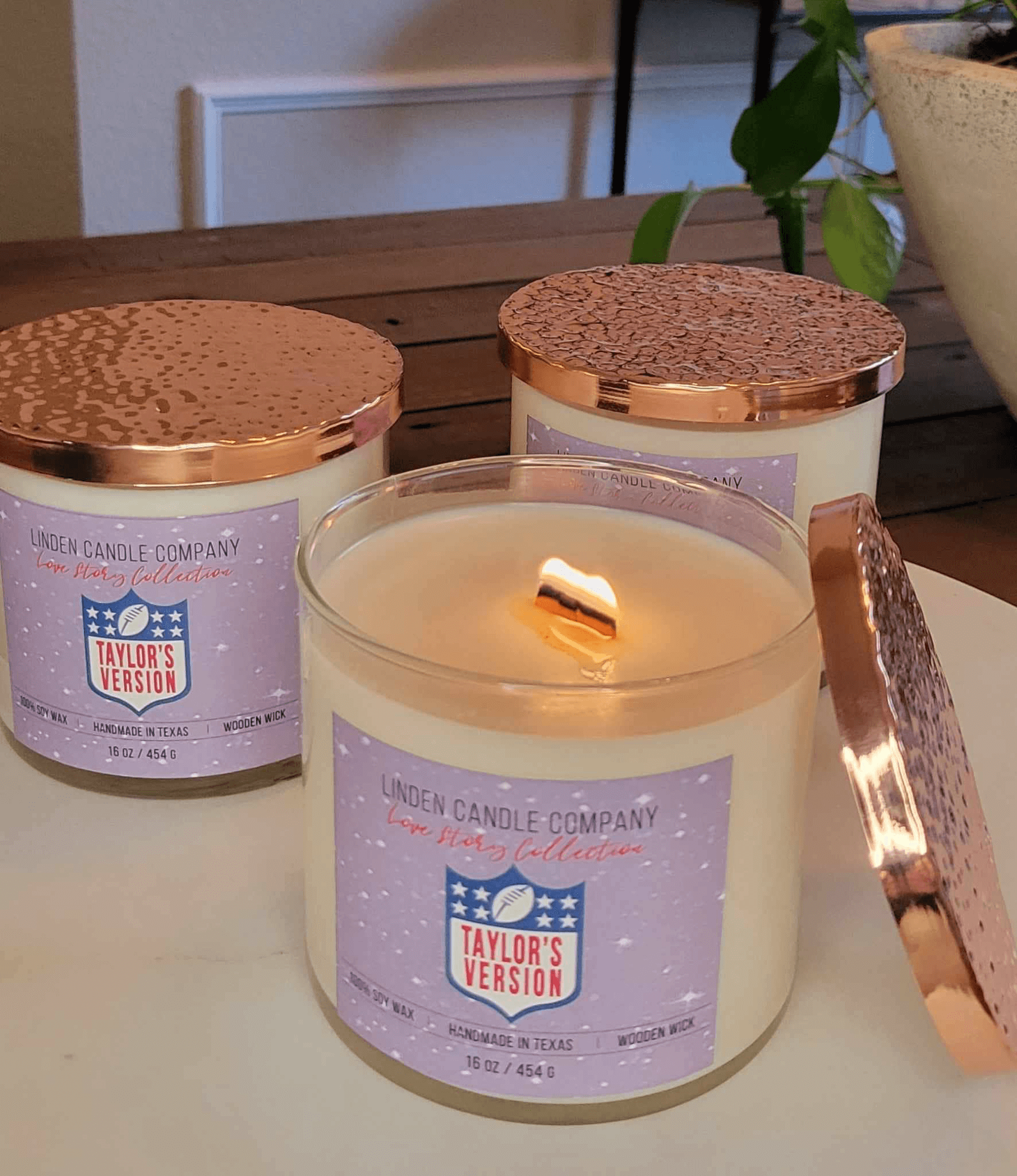 Three Taylor's version candles with one burning wood wick.