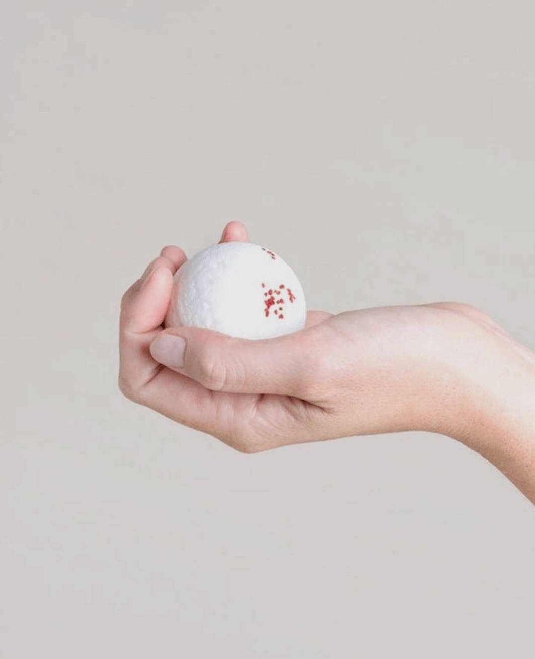 A girl holding a natural bath bomb in her hand.