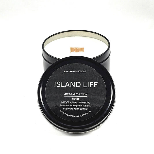 Black travel tin, wood wick, soy candle with a black label in island life scent.